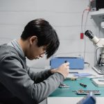 Técnico utiliza um microscópio para reparar um dispositivo eletrônico em um laboratório.