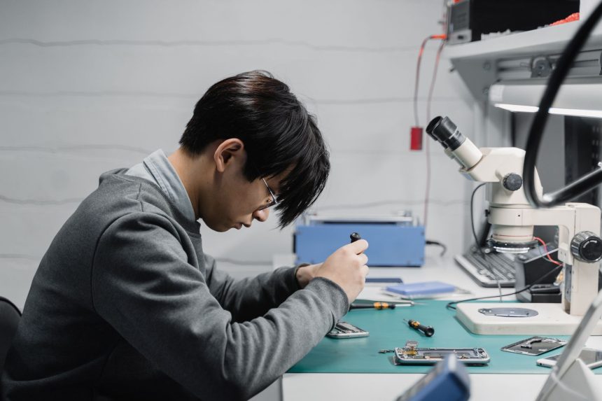 Técnico utiliza um microscópio para reparar um dispositivo eletrônico em um laboratório.