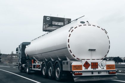 Caminhão-tanque transporta combustível por uma rodovia, visto por trás.