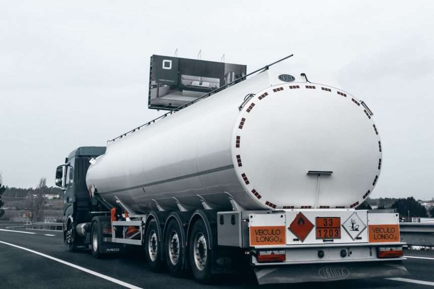 Caminhão-tanque transporta combustível por uma rodovia, visto por trás.