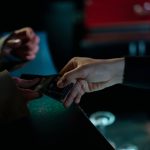 Mãos trocando ingressos de cinema em um ambiente interno.