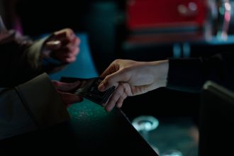 Mãos trocando ingressos de cinema em um ambiente interno.