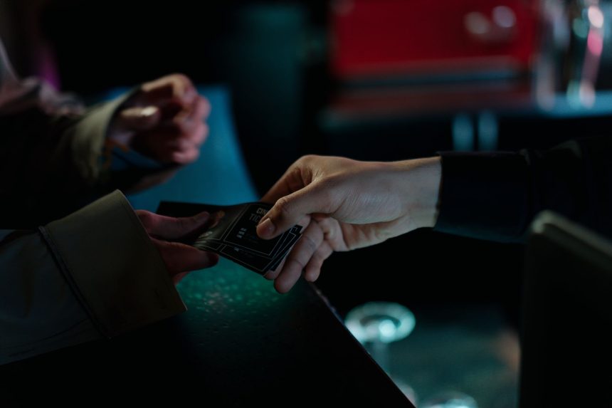 Mãos trocando ingressos de cinema em um ambiente interno.