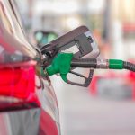 Bico de abastecimento inserido no tanque de um carro em um posto de combustíveis.