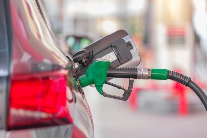 Bico de abastecimento inserido no tanque de um carro em um posto de combustíveis.