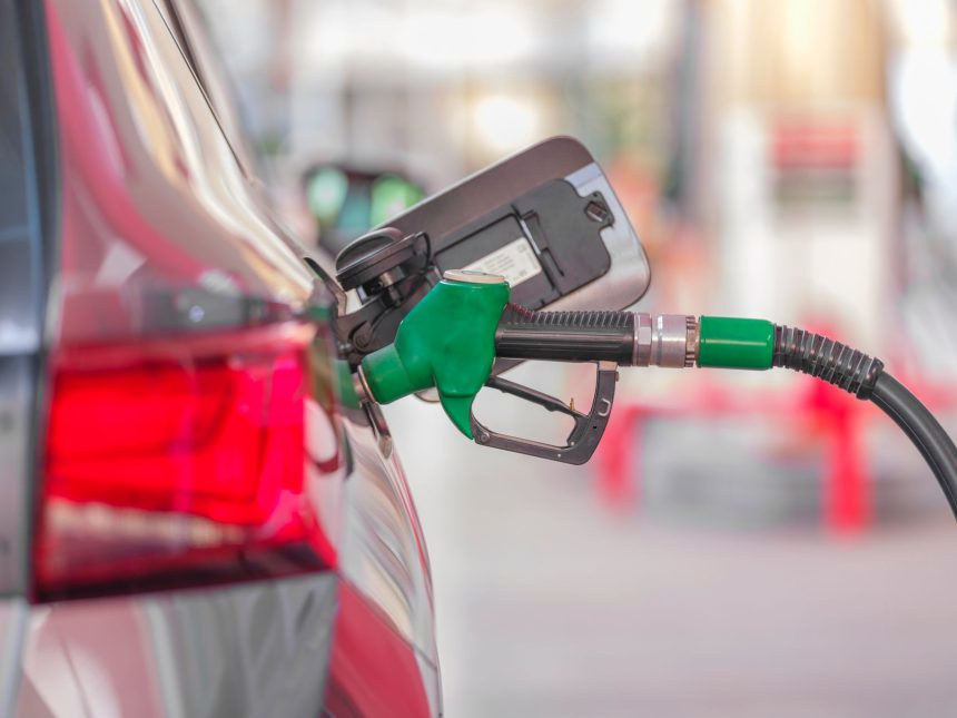 Bico de abastecimento inserido no tanque de um carro em um posto de combustíveis.