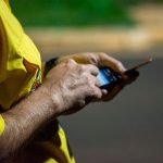 Mãos usam um smartphone ao ar livre durante a noite em Londrina, no Paraná.