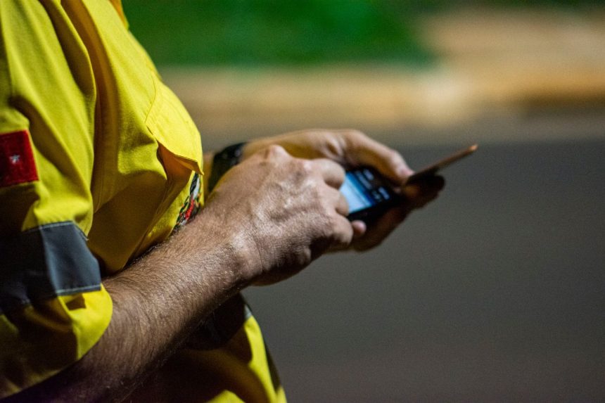 Mãos usam um smartphone ao ar livre durante a noite em Londrina, no Paraná.