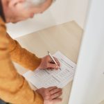 Homem idoso marca seu voto em uma cabine de votação dentro de uma seção eleitoral