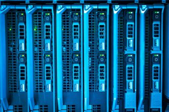 Racks de servidores iluminados em azul dentro de um datacenter.